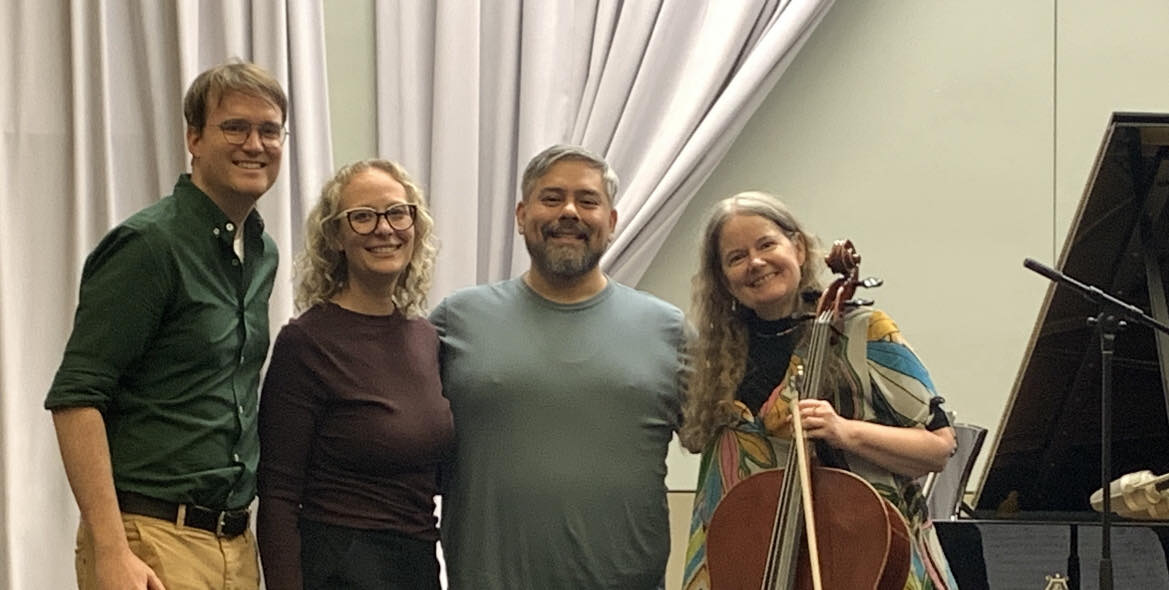 The ensemble posing for a photo in a recital hall.